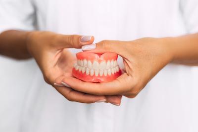 Dentist holding set of implant dentures in Brandon, FL