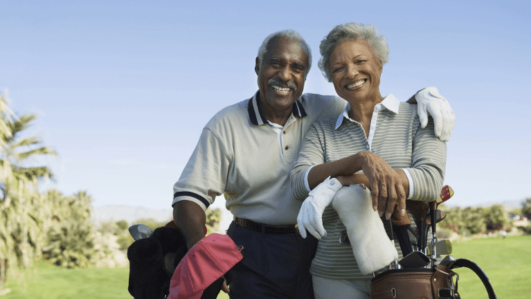A smiling elderly couple on the golf course | dental bridges Brandon FL