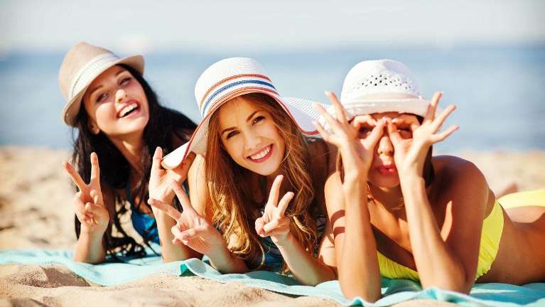 A group of smiling women posing on the beach