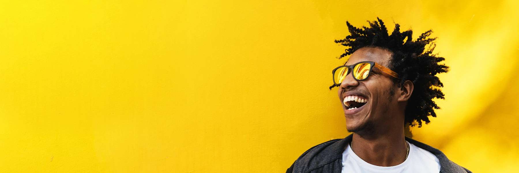 Man with dental crowns smiling against a yellow wall in Brandon, FL